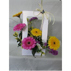 Жълти и розови гербери аранжирани в бяла чантичка.