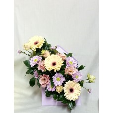 Гербери, еустома и хризантема в нежни, пастелни тонове, аранжирани в кутия плик.