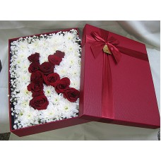 Буква от рози аранжирани в кутия.